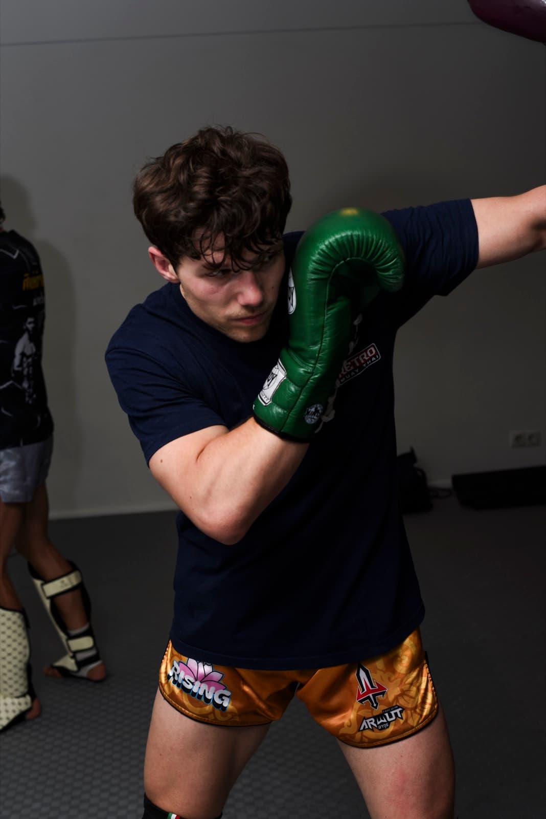 Paul, Lead Coach, in Kampfhaltung mit grünen Handschuhen im Trainingsraum